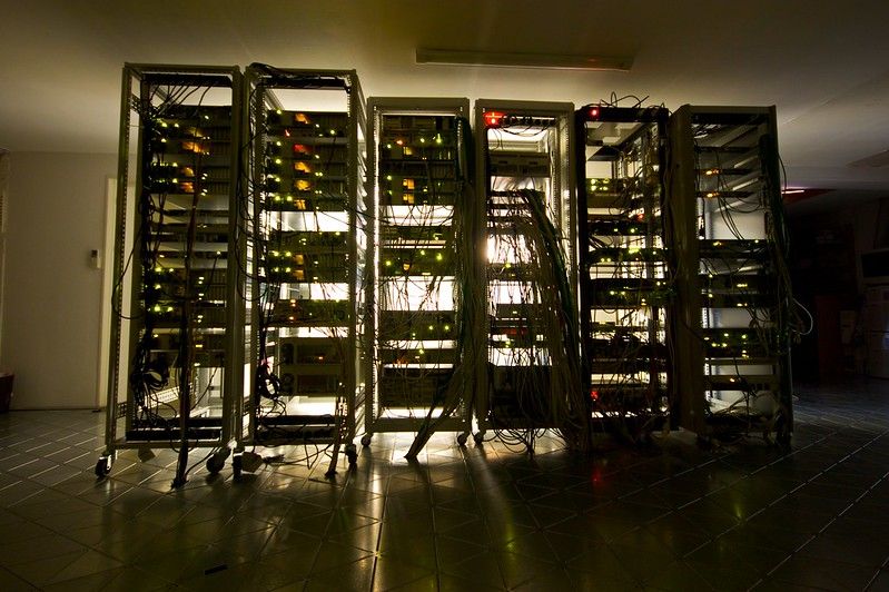 Rack of servers and networking equipment, lit with white light from the back.